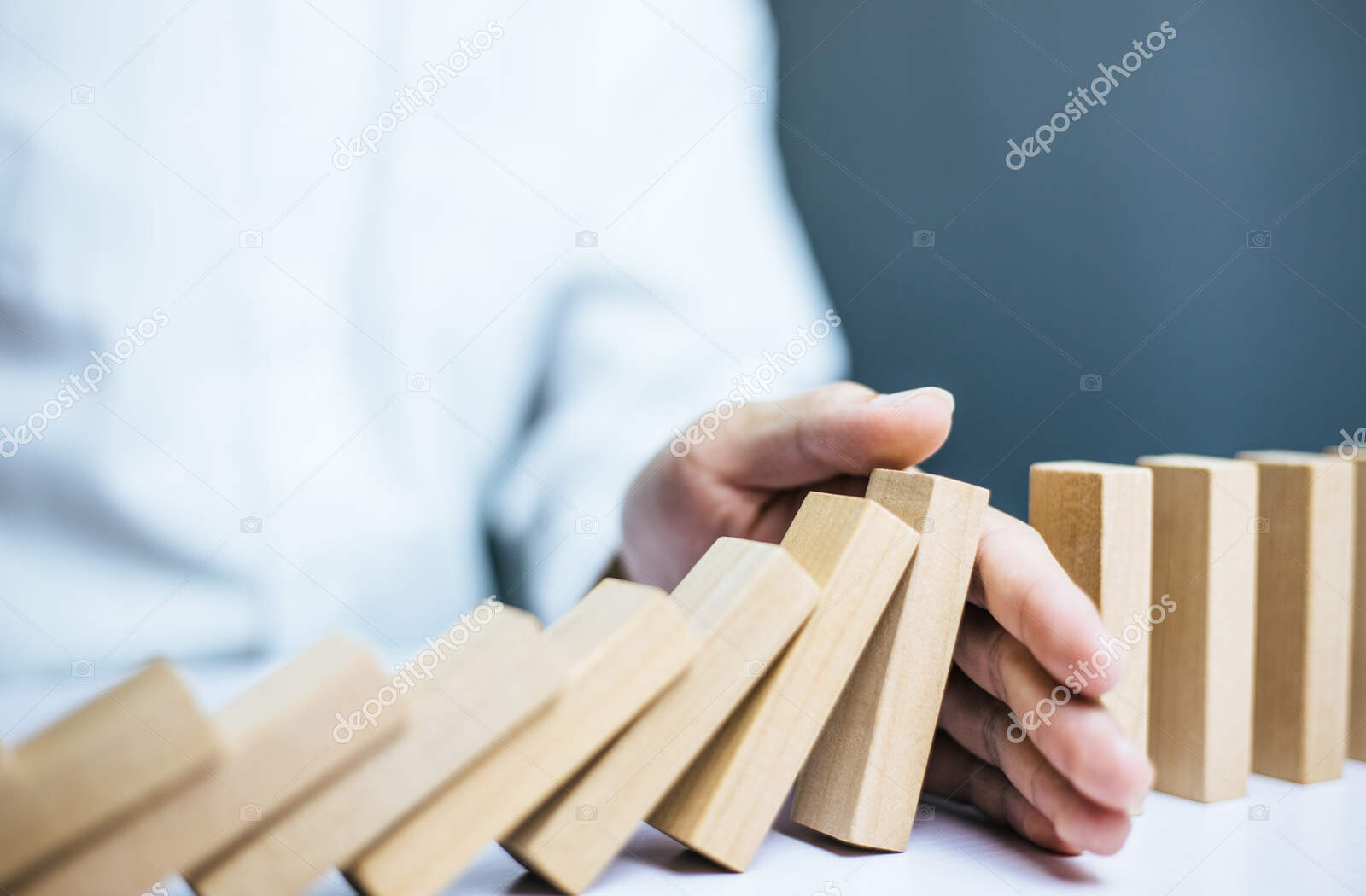 problem solving, close up hand of businessman stopping falling blocks on table.